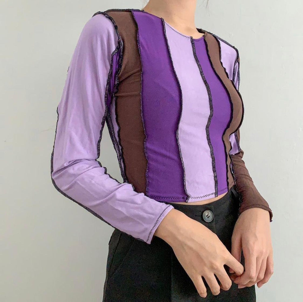 Strips of different shades of purple and brown vertically beside each other with black thread, long sleeve top.