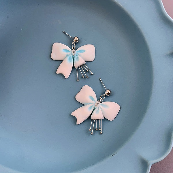 Pink bow earrings with hints of blue, 5 dangly metal balls attached.